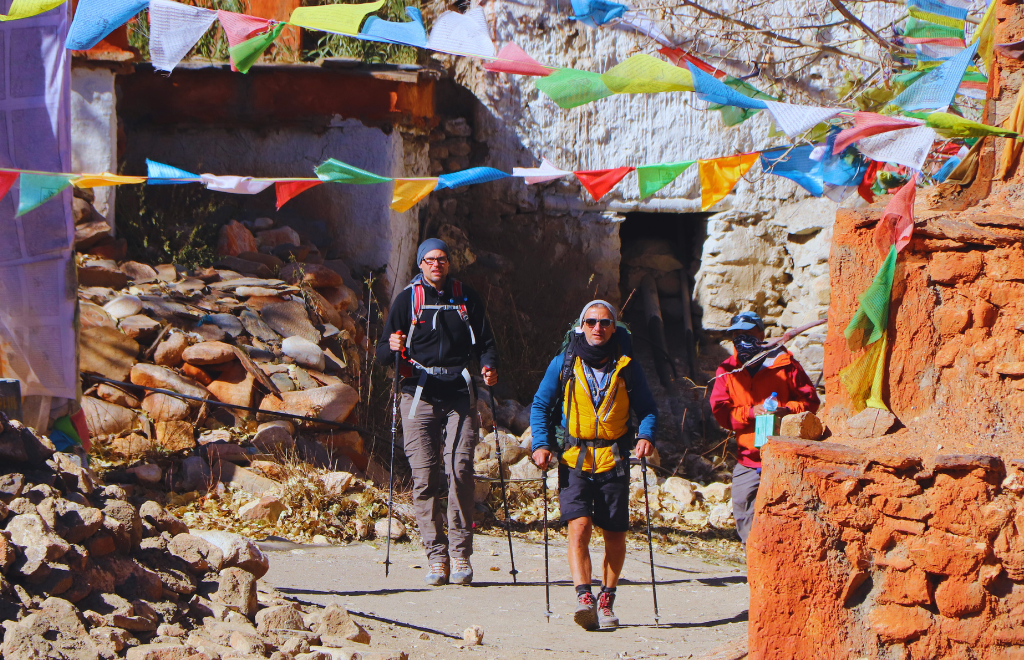 Trekking group ascending toward Damodar Kunda Upper Mustang under clear Himalayan skies and desert cliffs