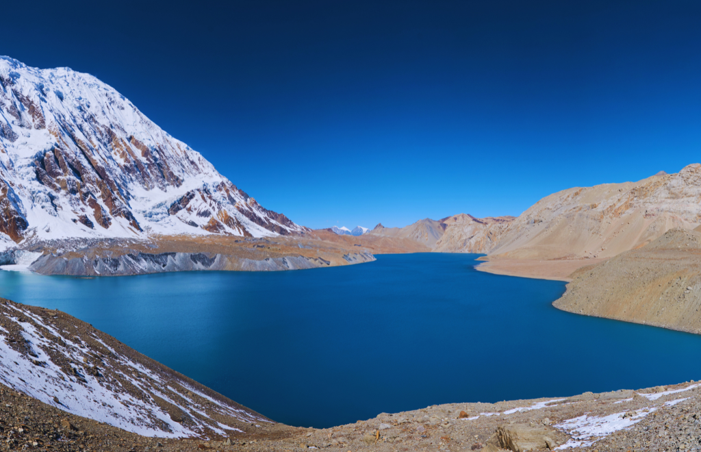 Turquoise Tilicho Lake nestled among snowy peaks along the Annapurna trekking route, Nepal